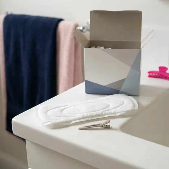 An opened box of adult pads on a bathroom shelf