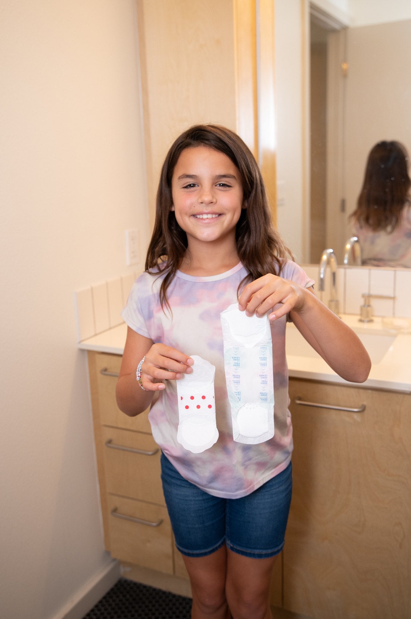 Girl holding period products in a bathroom